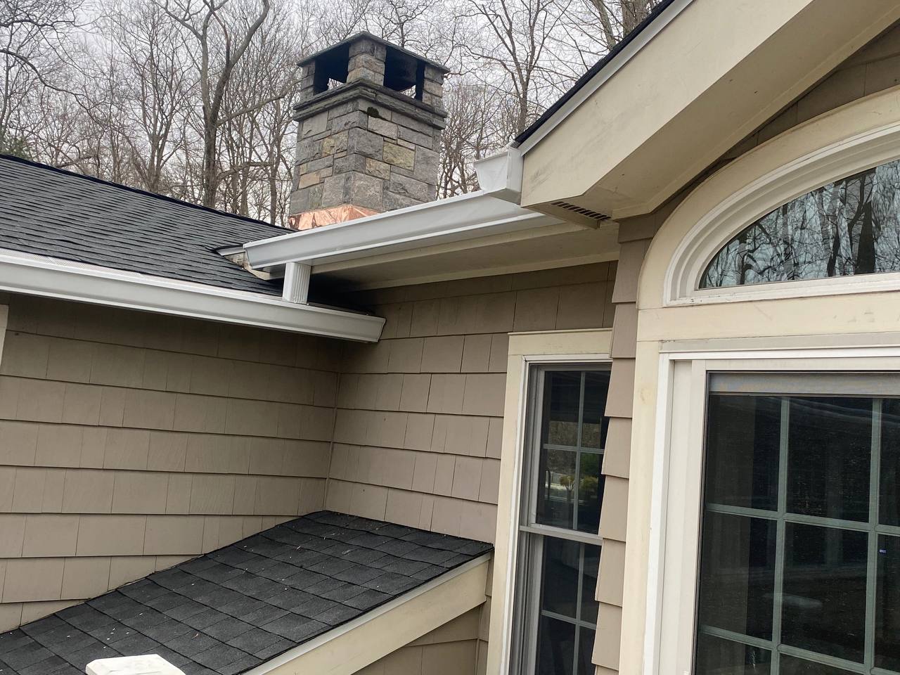 Gray roof with white seamless gutters professionally installed by Riga Home Pro
