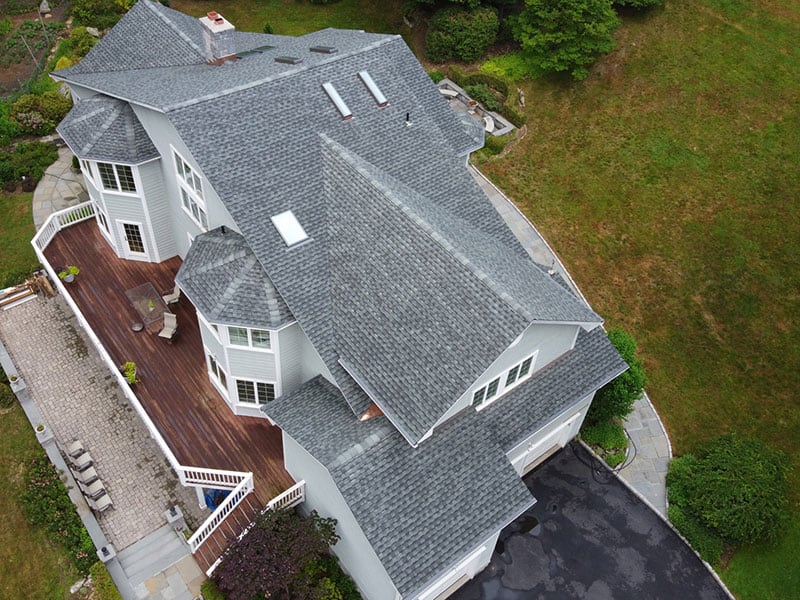 Gray asphalt shingle roof with five skylights and chimney installed by Riga Home Pro, expert residential roofing contractors in Fairfield County, CT